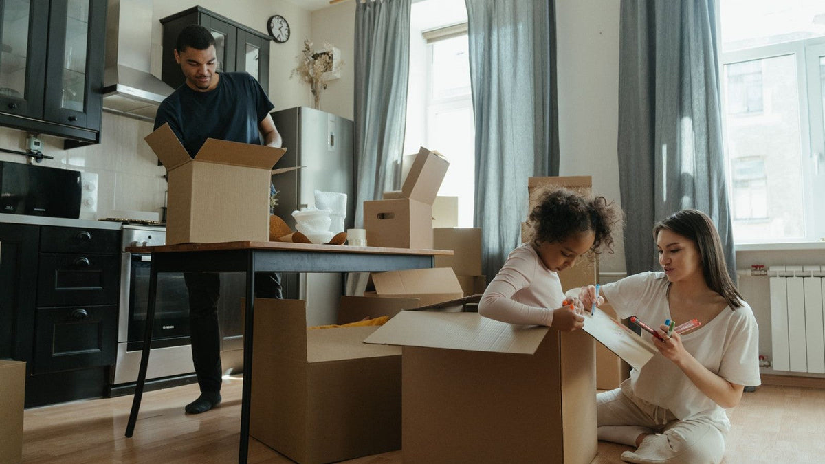 A family unpacking cardboard boxes and kitchenware in a new home