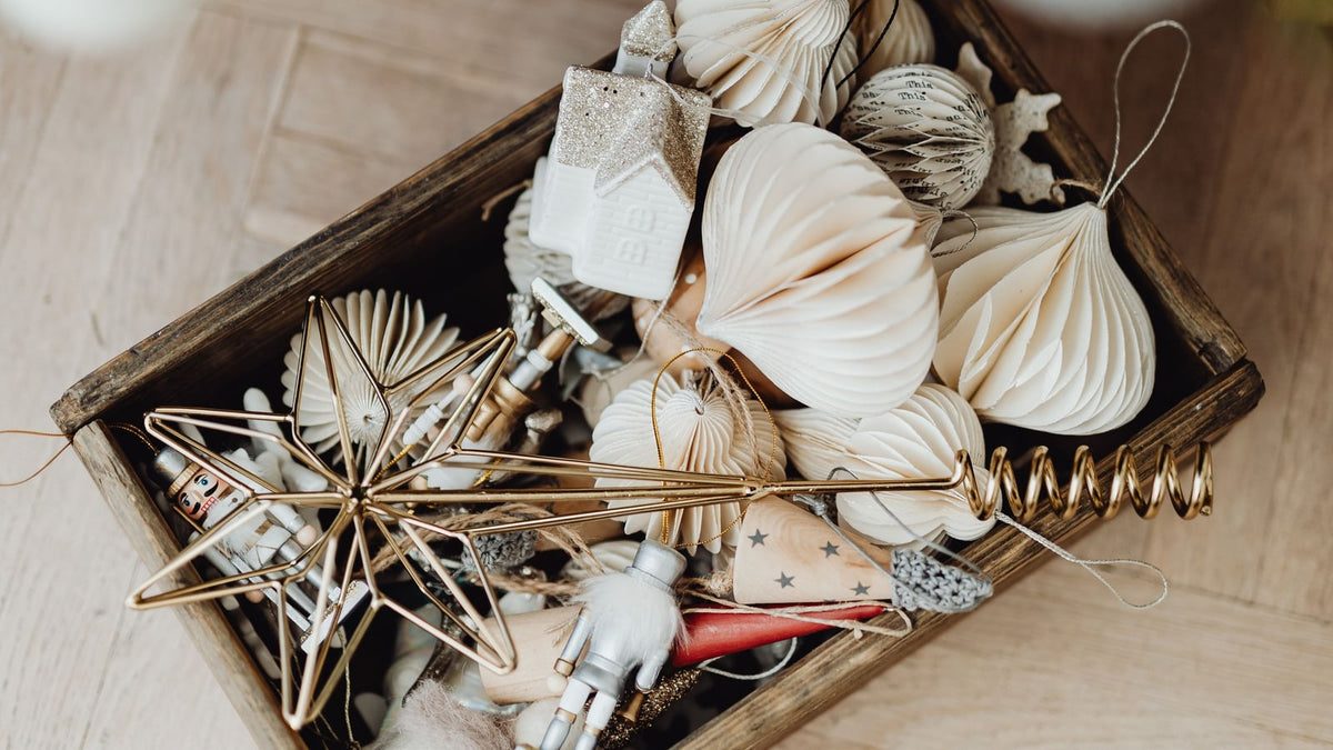 White and gold seasonal ornaments gathered in a wooden box before sorting and protective packing