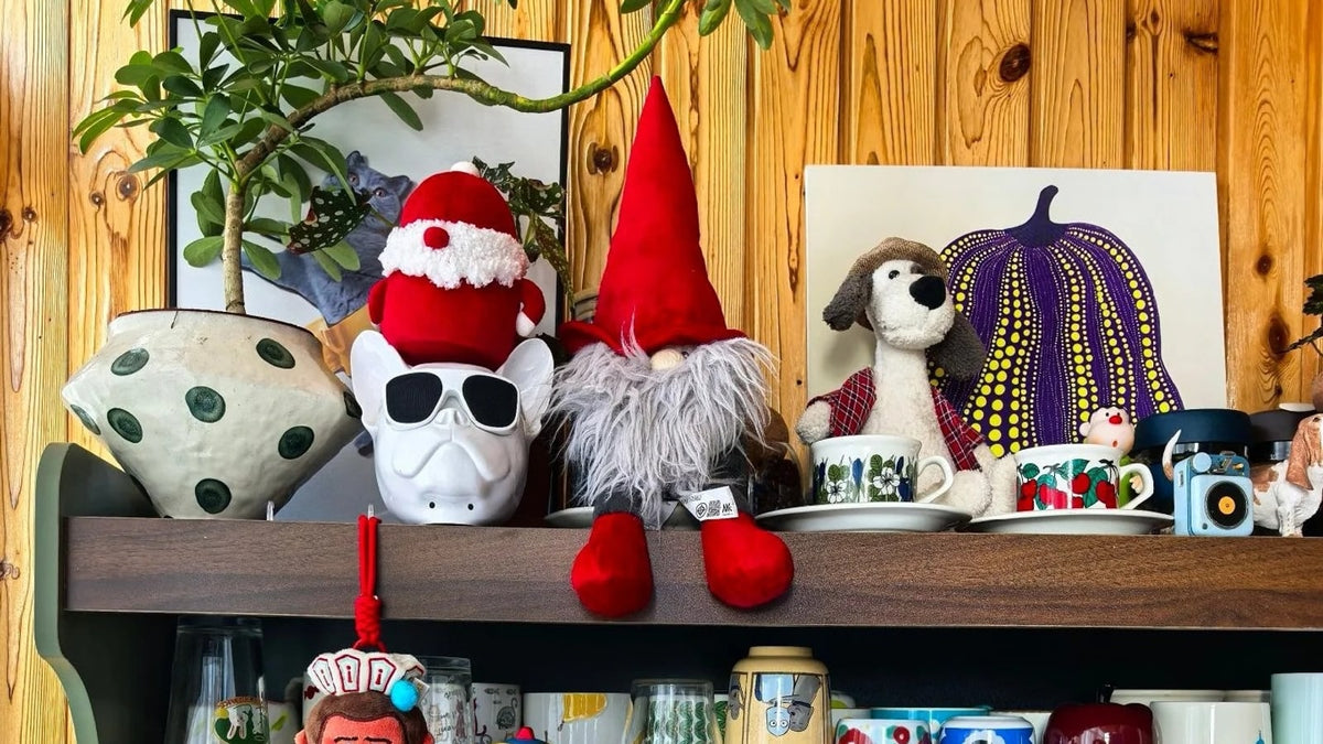 Santa hat and red-hatted Christmas gnome among cups on a real home coffee shelf