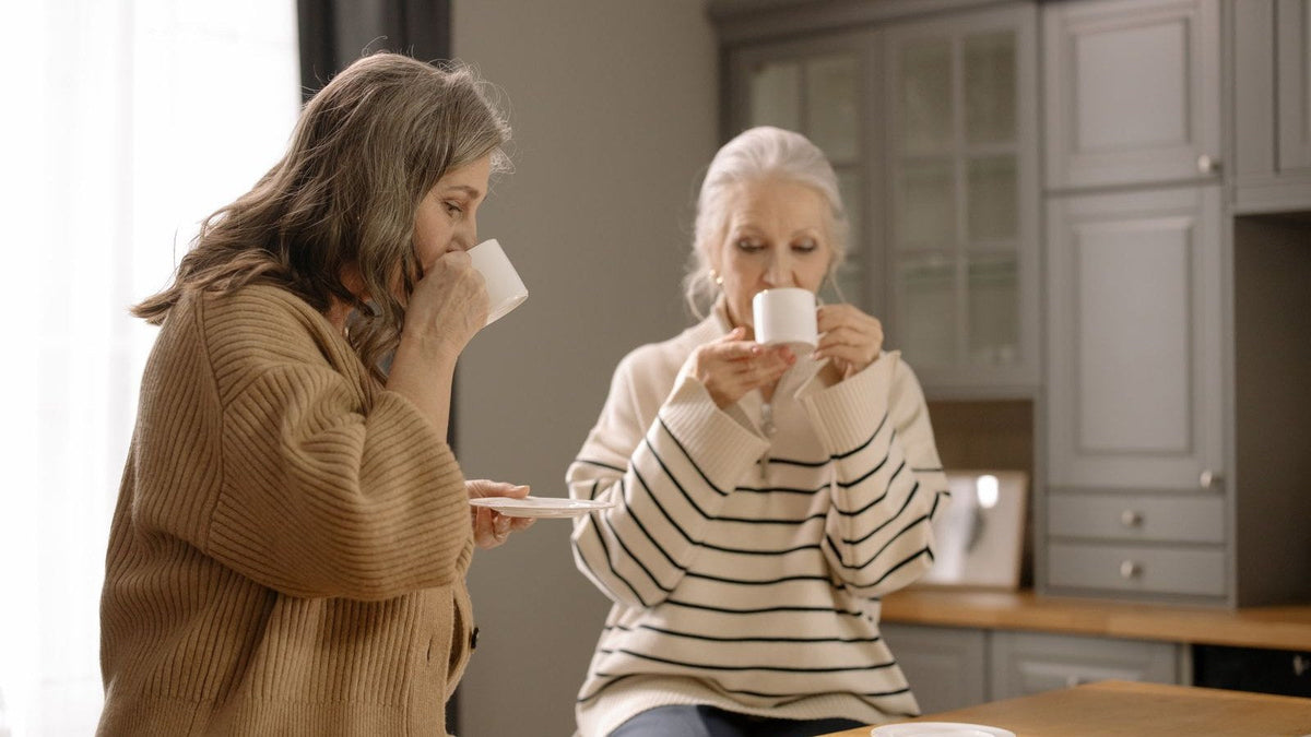 Two women drinking coffee together in a warm kitchen