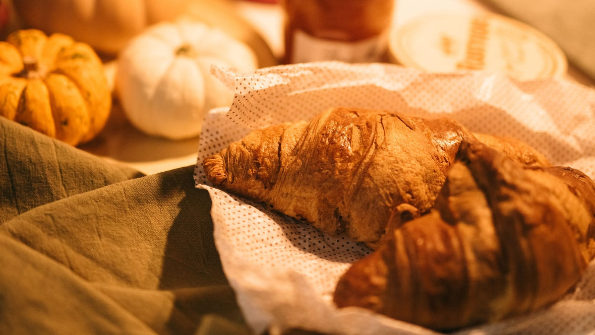 Croissants and small pumpkins in warm light on a kitchen counter