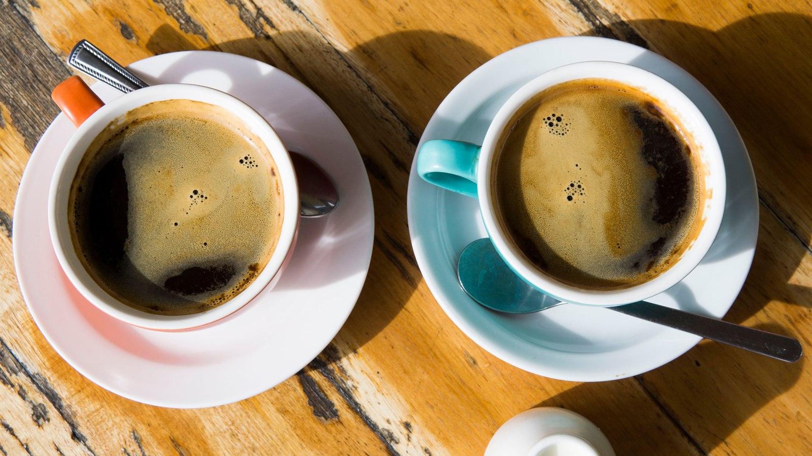 Two cups of black coffee on a wooden café table for drink comparison