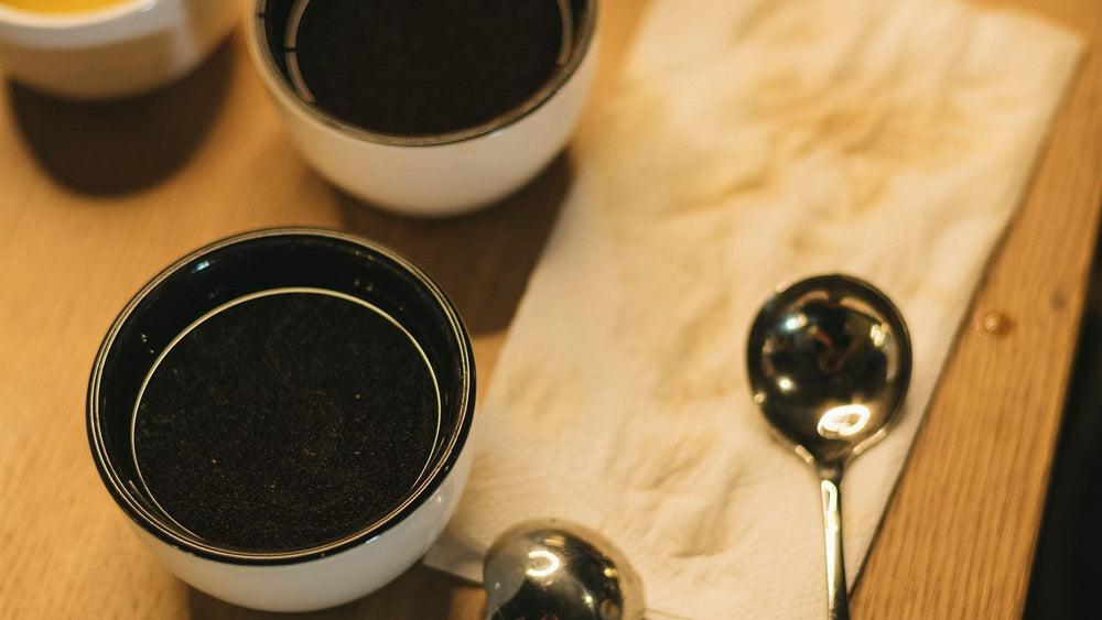 Coffee cupping bowls and spoons arranged on a warm wooden table