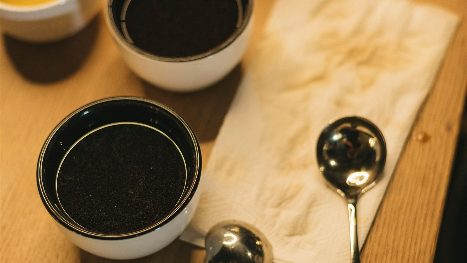 Coffee cupping bowls and spoons arranged on a warm wooden table