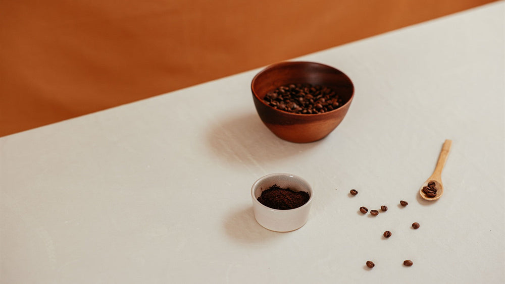 Bowls of whole coffee beans and ground coffee arranged for comparison