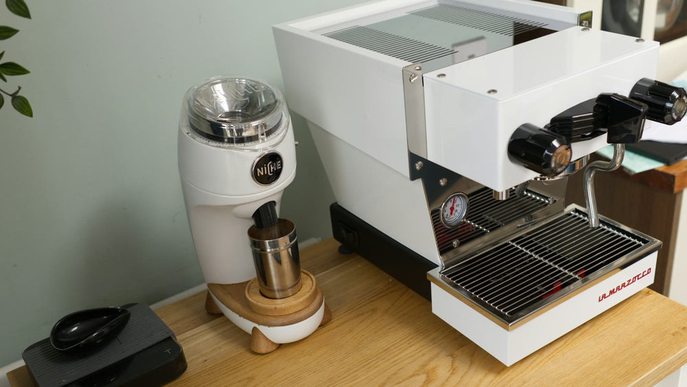 White espresso machine and grinder arranged on a home coffee counter