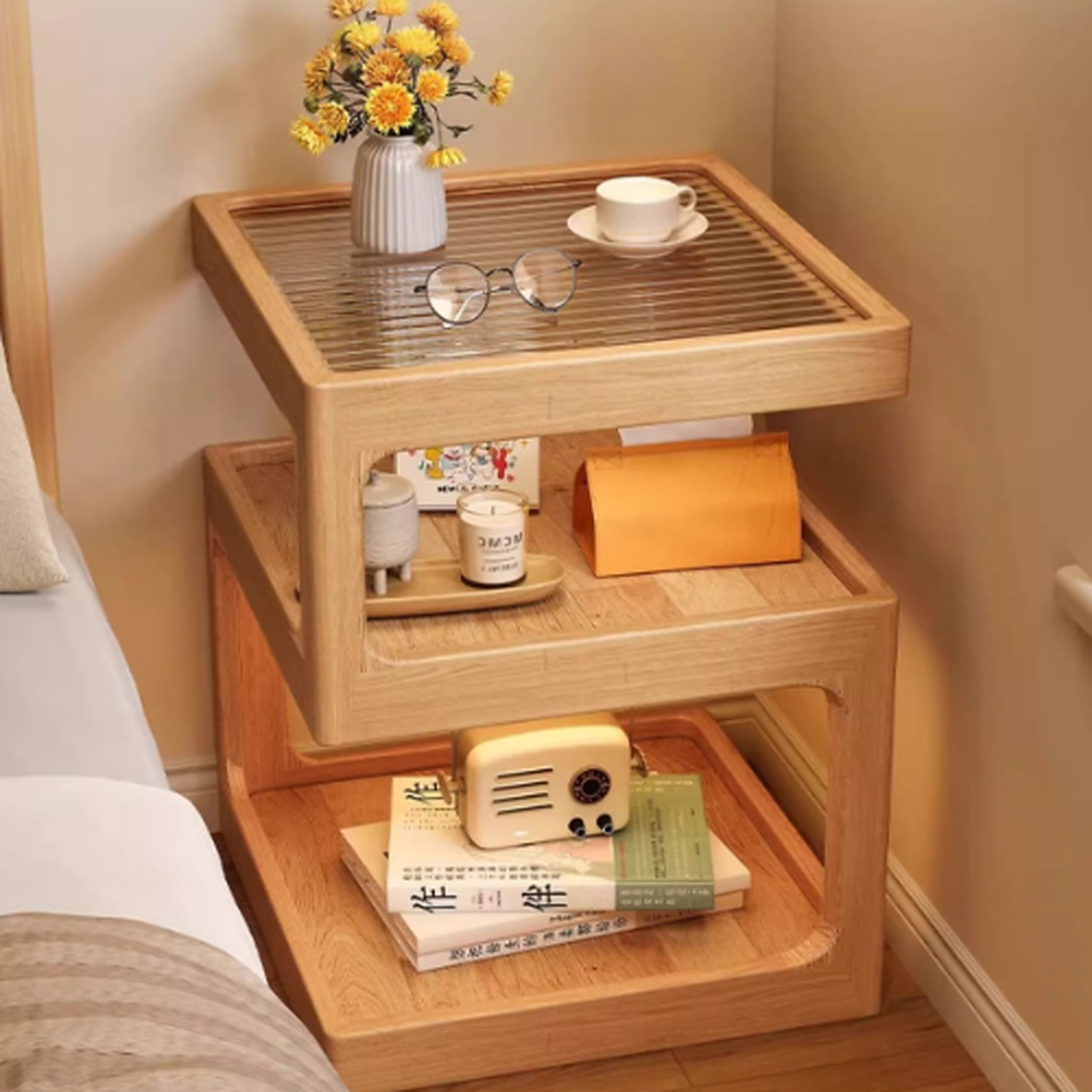 Natural finish three-tier coffee side table beside a bed with cups and small accessories