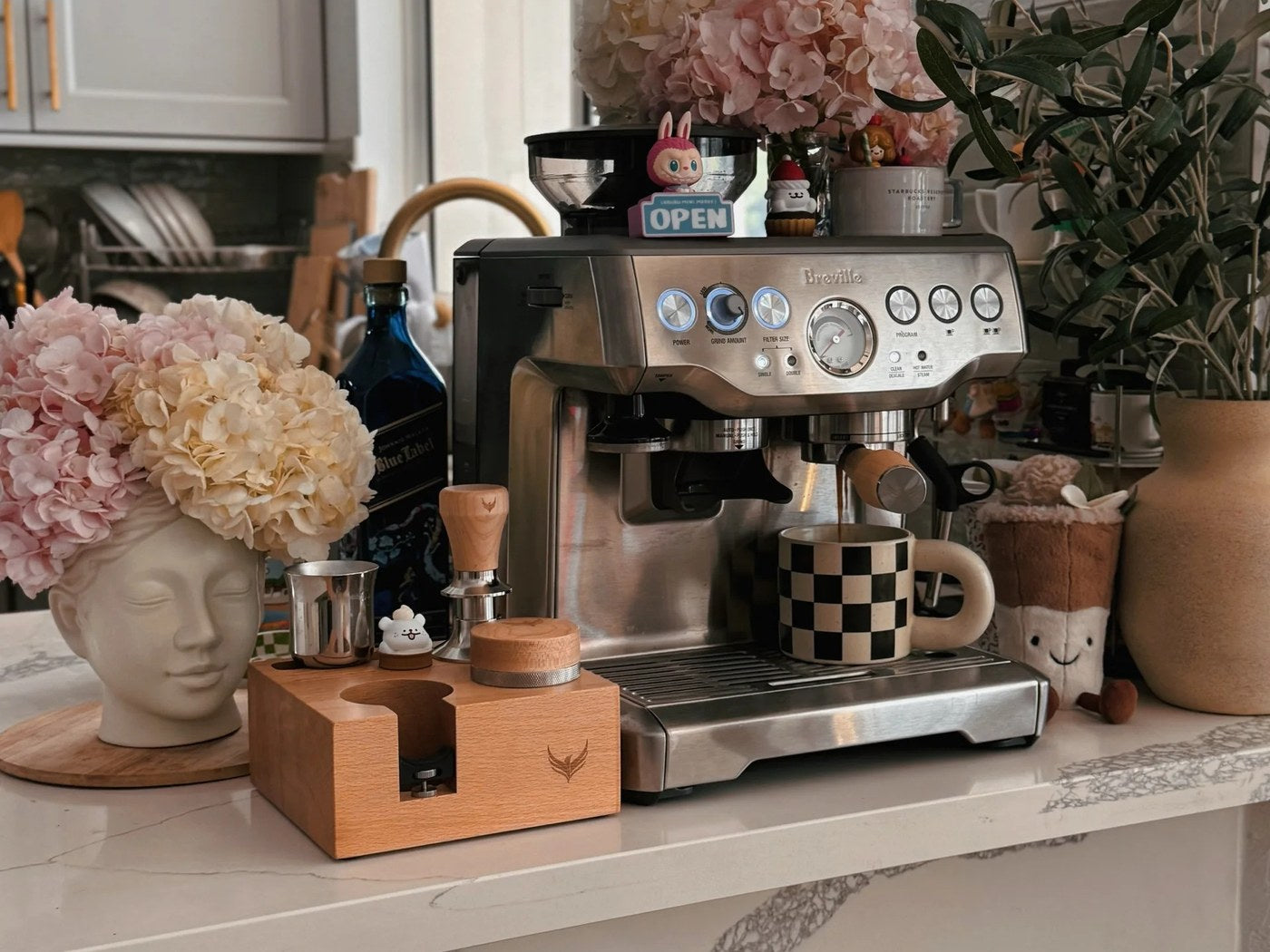 Window-side espresso station with flowers placed beyond the machine work area